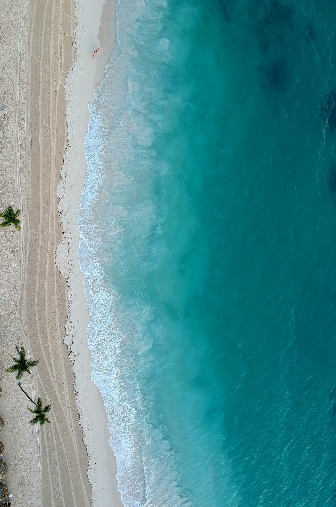 Overhead view of surf along a pale beach